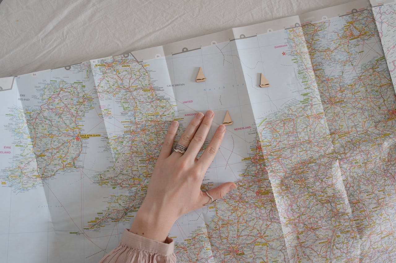 A hand on a map suggests travel and exploration, ideal for wanderlust vibes.